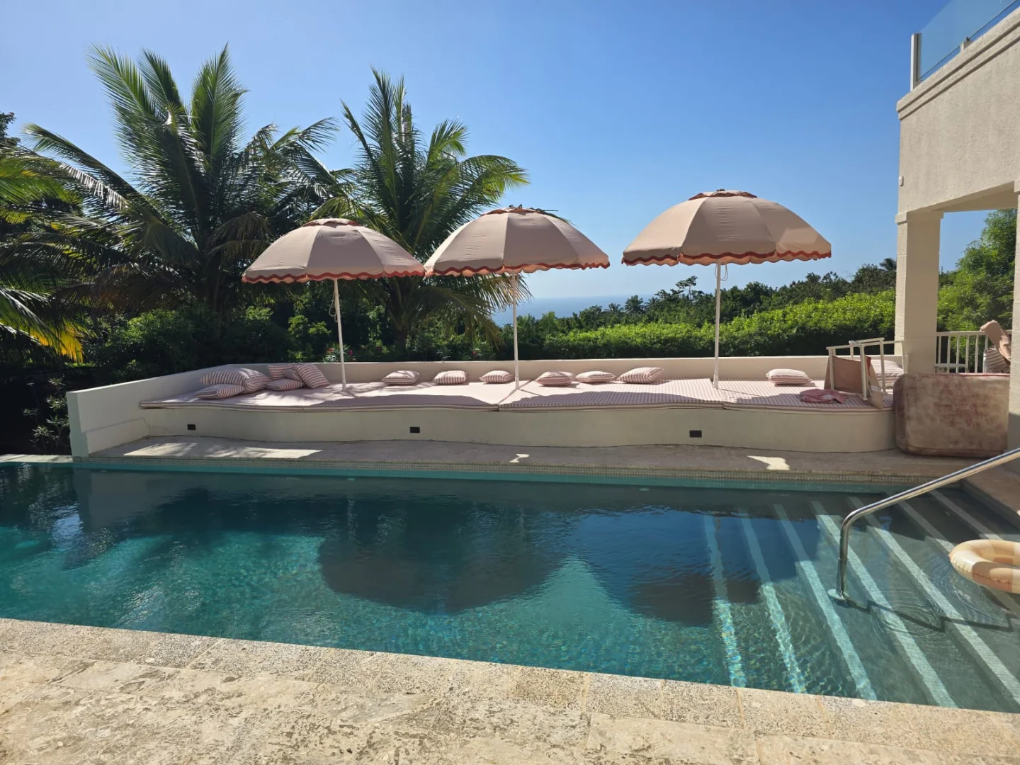 Poolside daybed with striped cushions and fringed umbrellas made in Barbados