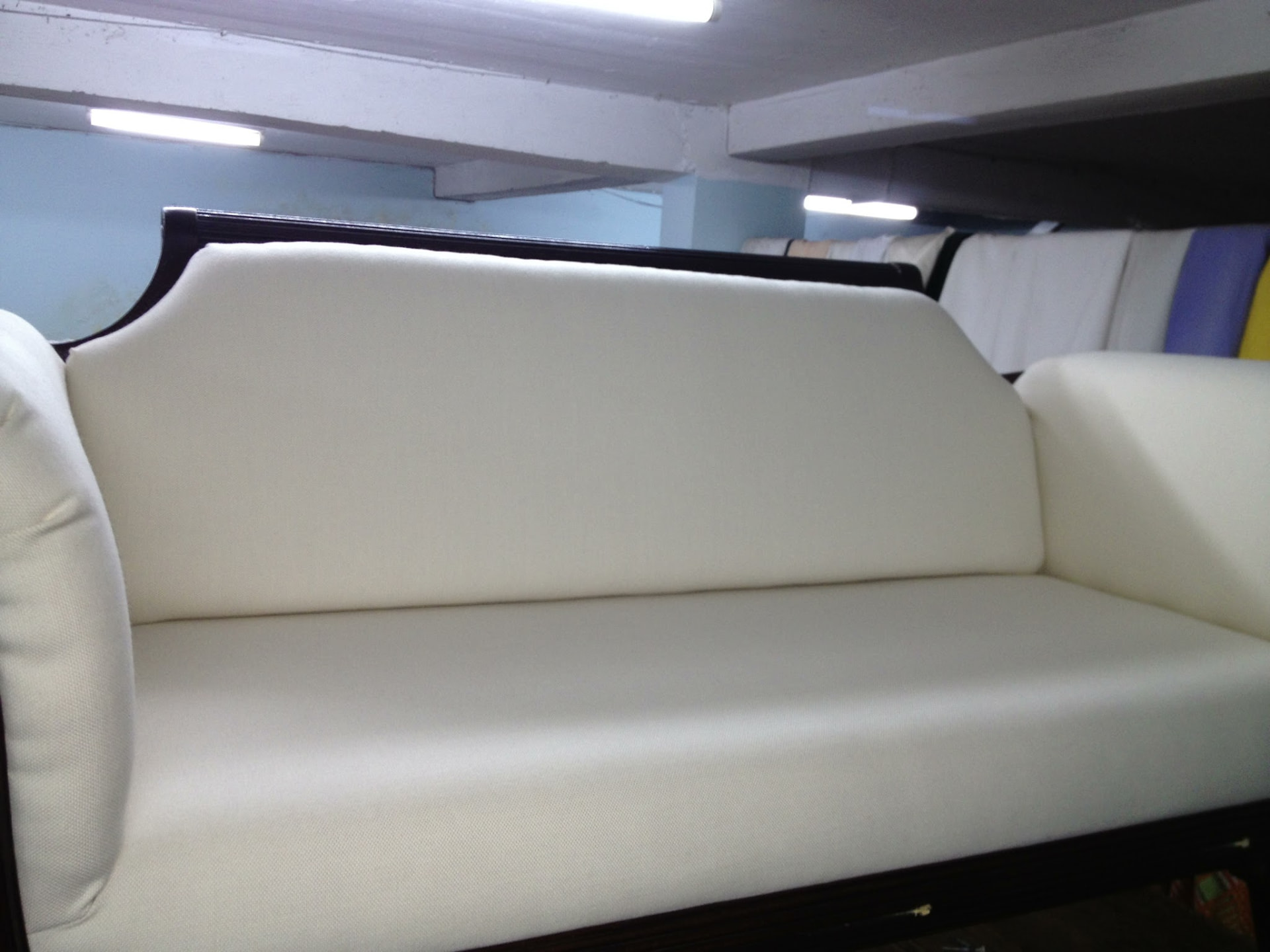 Antique mahogany-framed sofa reupholstered in ivory fabric at the Hinds Upholstery workshop